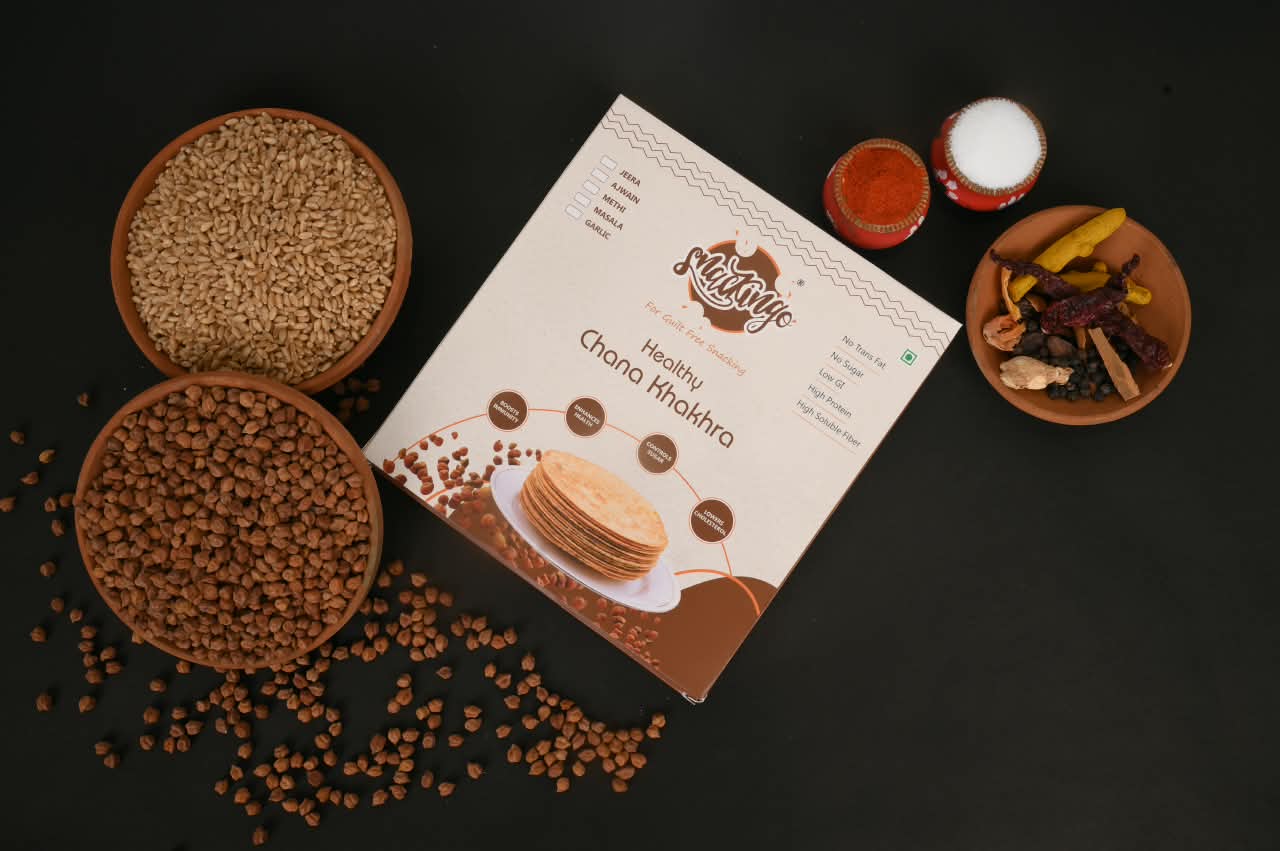 Desi chana, wheat and whole spices around a Snackingo Chana box