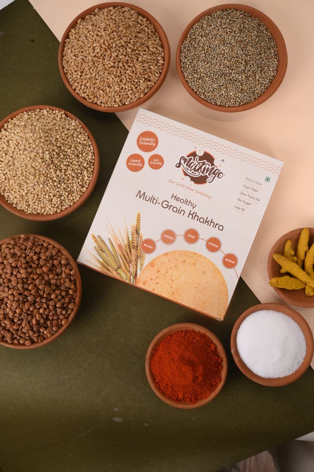 Bowls of bajra, jowar, ragi, chana, wheat and spices around a Snackingo Multi-Grain box